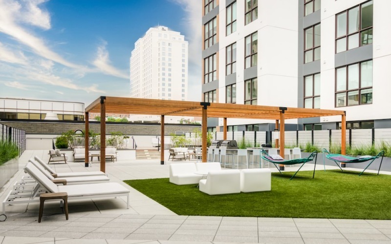 Outdoor terrace with white furniture, hammocks, and a grilling station.