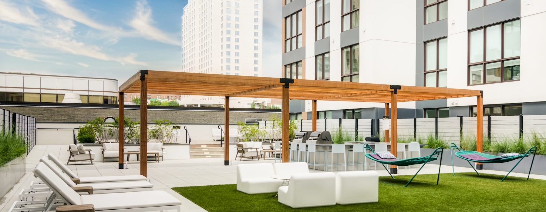 Outdoor terrace with white furniture, hammocks, and a grilling station.