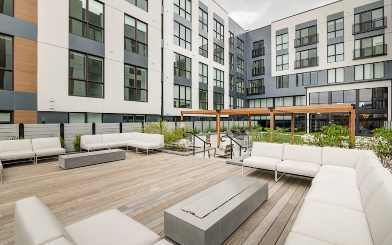 Courtyard with large couches, firepits and wood flooring.