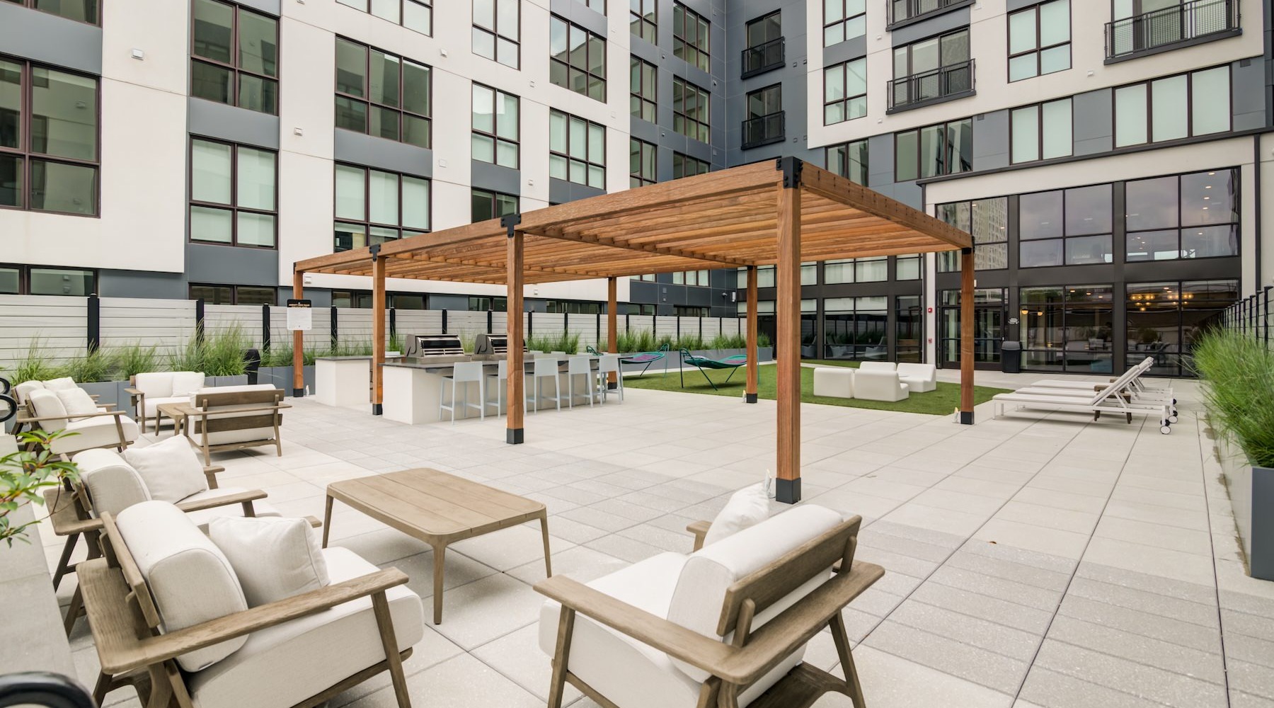 Motif Courtyard Bright courtyard with white lounge chairs and a grilling station.
