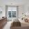 Modern bedroom design with a bed, dresser, and large windows.